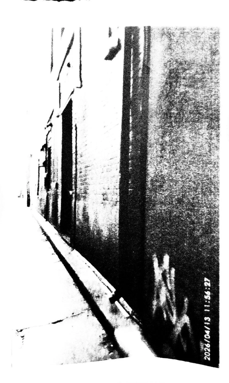 A narrow passage along a brick wall with graffiti, 13 April 2026.