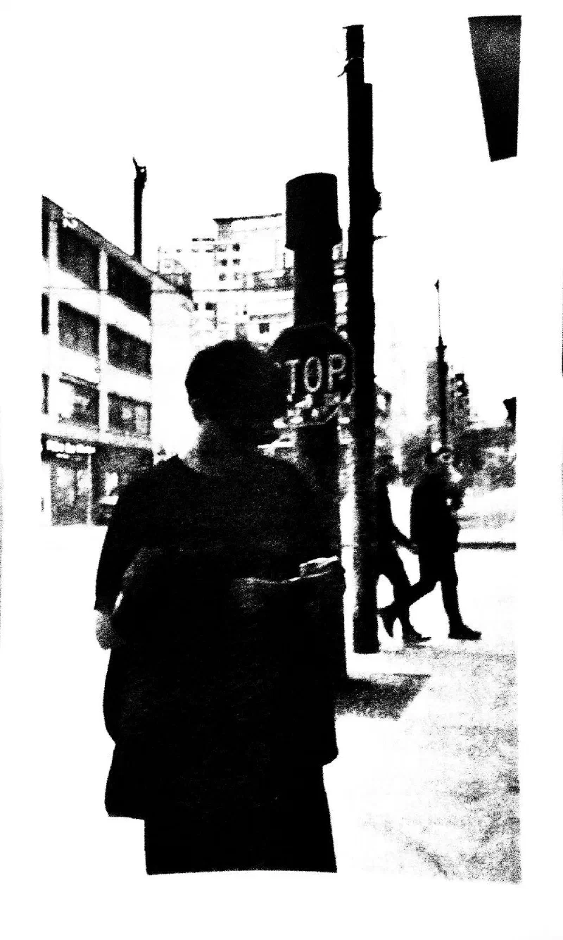 A pedestrian seen from behind at a corner with a stop sign.
