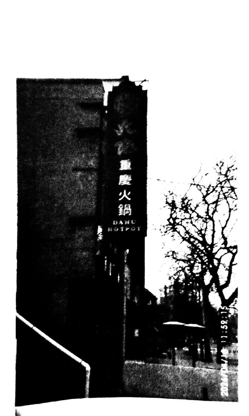 The Dahu Hotpot sign on a dark building, beside bare trees.