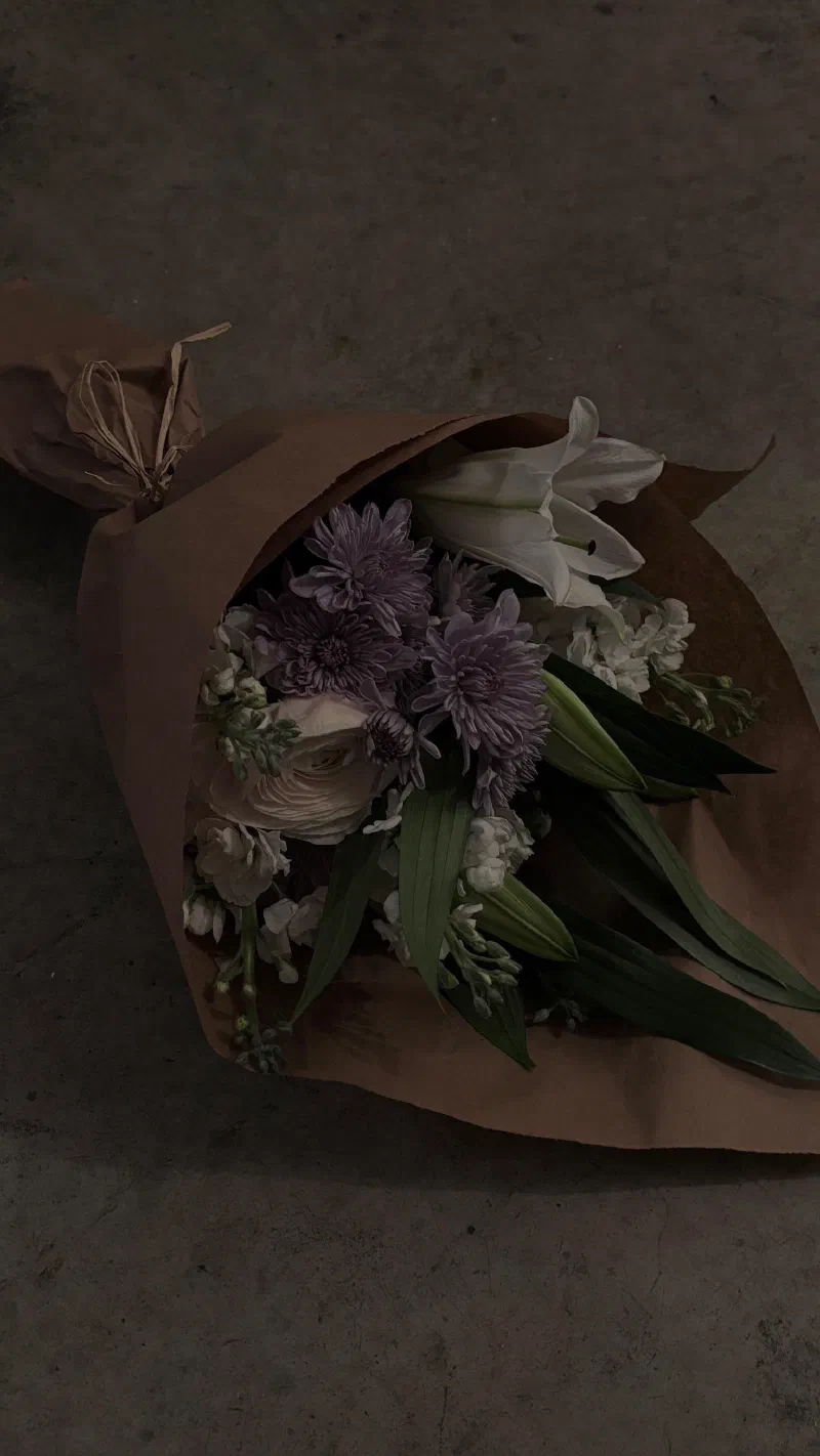 A bouquet in brown paper on a concrete floor, February 2026.