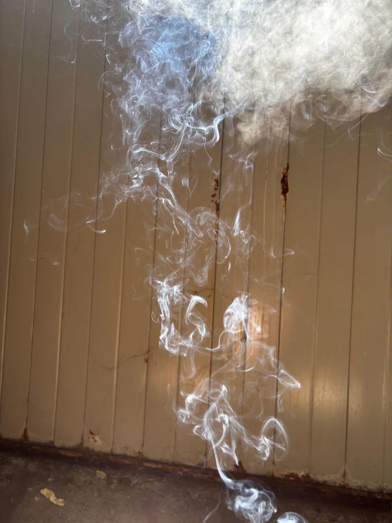 Smoke rising against a metal wall, July 2026.