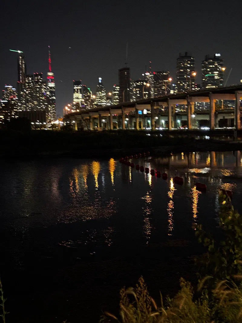 The Toronto skyline at night, reflected in the water, August 2026.