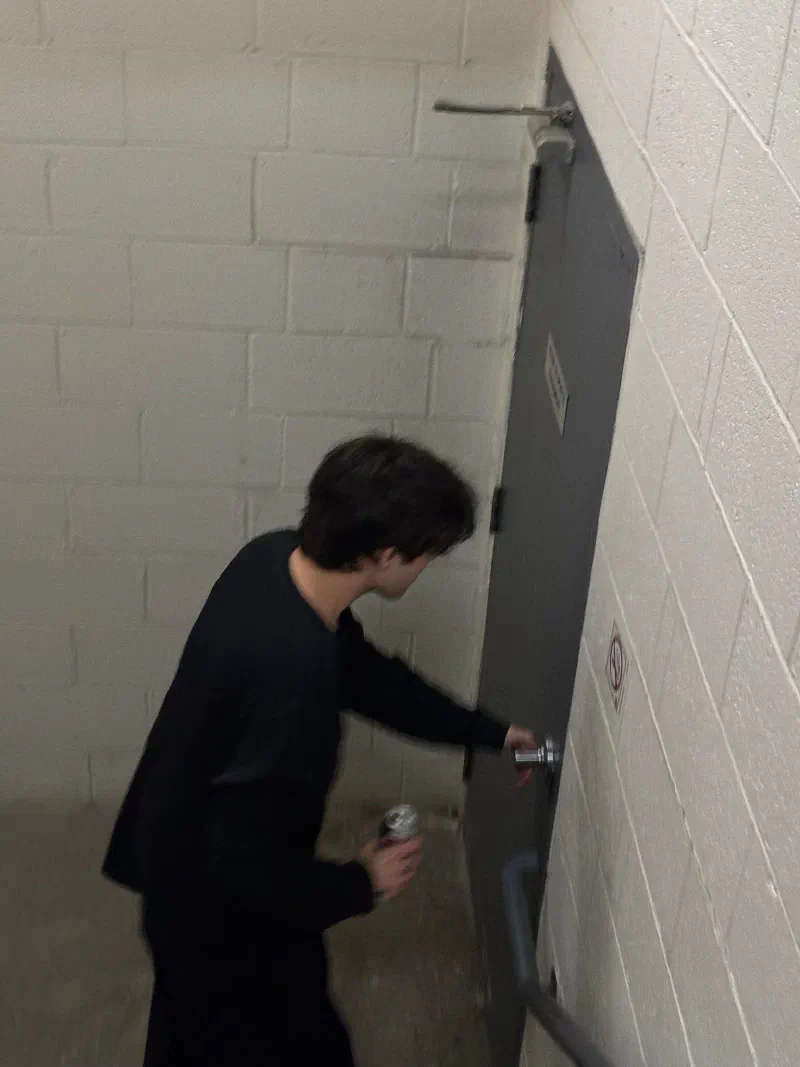 Andrada opening a stairwell door, a can in one hand.
