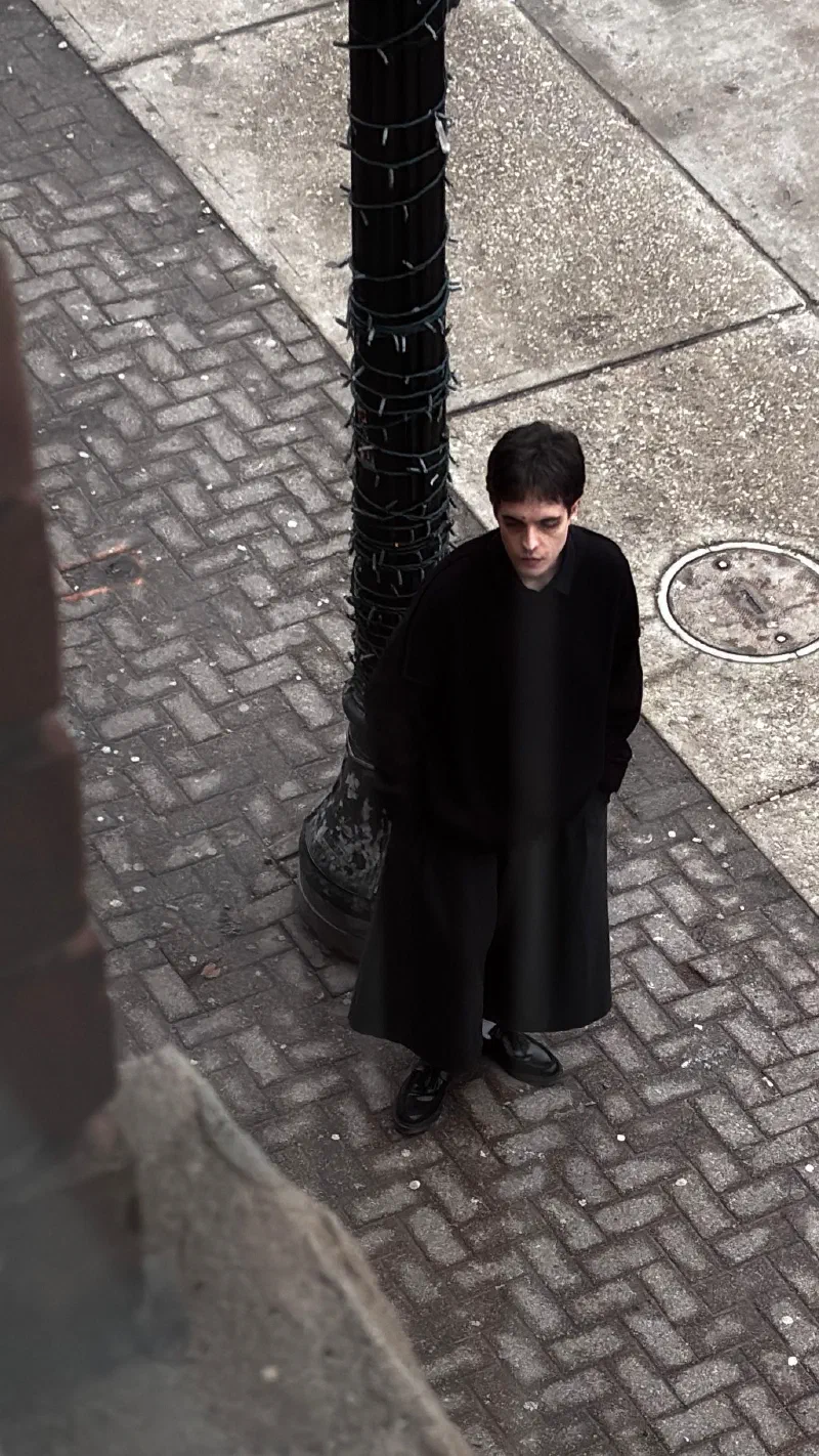 Andrada at the same lamppost, hands in his pockets, photographed from above, March 2026.