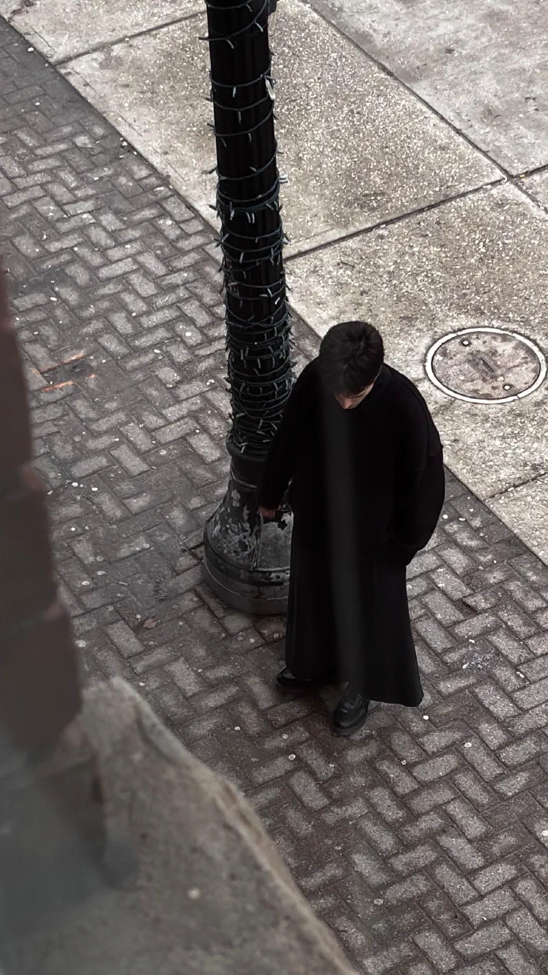 Andrada at the lamppost with his head bowed, March 2026.