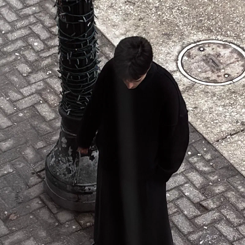 A closer view of the same moment: Andrada, head bowed, beside the lamppost.