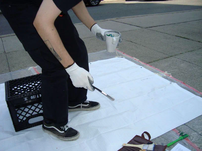 Andrada painting on the sidewalk during the 2024 Yorkville Murals festival, Toronto.